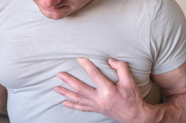 Adam göğsüne tutundu. Beyaz bir arka planda kalp krizi anjini. Hasta herif. Tıbbi muayene. Kalp hastalığı