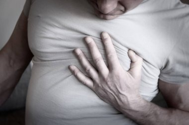 Adam göğsüne tutundu. Beyaz bir arka planda kalp krizi anjini. Hasta herif. Tıbbi muayene. Kalp hastalığı