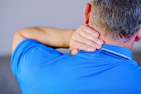 Pain in the neck, the man massages the place of inflammation with his hand