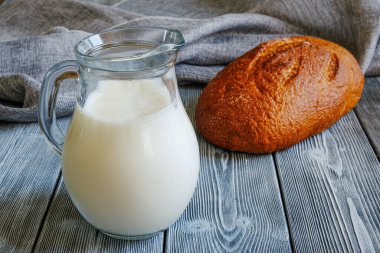 Masada basit yiyecekler, sütte süt ve taze pişmiş kabuklu ekmek. Tahtalardan yapılmış bir köy masası. Çadır bezi.