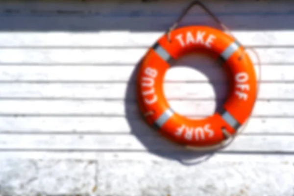 Background, blur, out of focus, bokeh. Orange rescue float. Lifebuoy on the wall of the building of the rescue station.