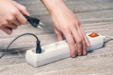 Ev sahibesi elinde fitili olan bir elektrik uzatma kablosu tutuyor ve cihazı prize bağlıyor.