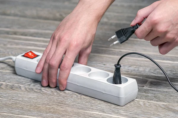 Ev sahibesi elinde fitili olan bir elektrik uzatma kablosu tutuyor ve cihazı prize bağlıyor.