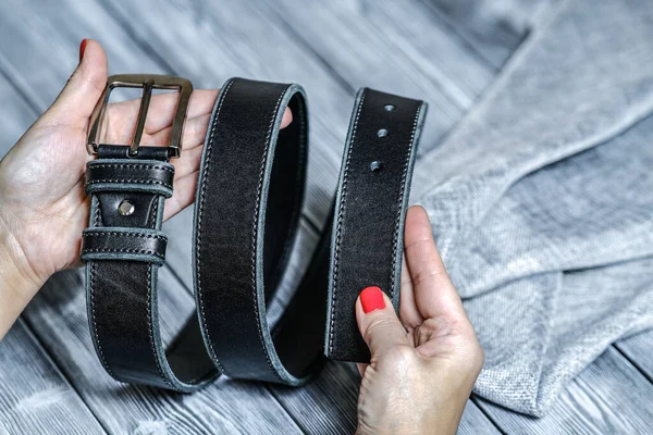 A young woman is holding a handmade belt made of genuine leather