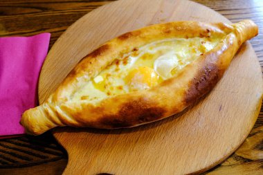 Tereyağı ve yumurta sarısı ile sıcak Gürcü ekmeği. Ahşap mutfak tahtasında servis edilmiş..