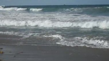 Okyanus dalgaları kumlu sahili yıkıyor.