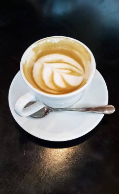 Fincan cappuccino bir desen değer karanlık bir tablo ile