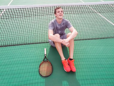 Yerde oturan erkek tenisçi