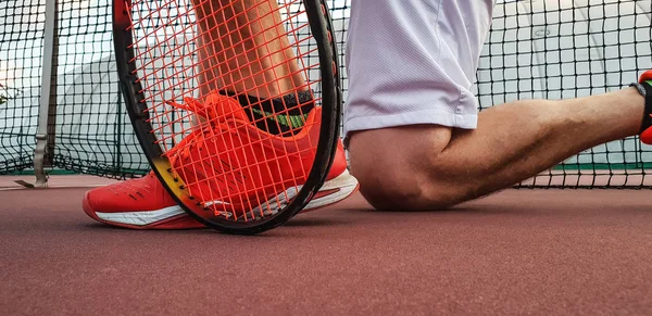 Legs of sportive man near the tennis racquet and balls
