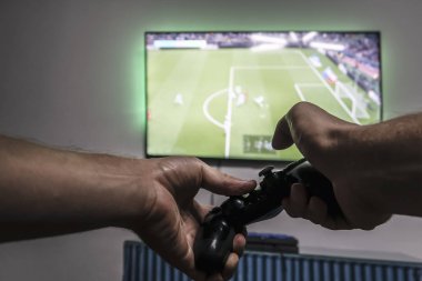Bir dakika dostum gamepad ile Pro Evolution Soccer tv ekranının önünde elinde. Bir oyun. Duvarda asılı geniş ekran tv