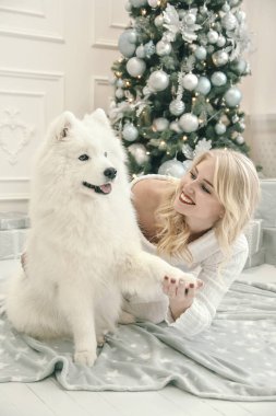 Noel ağacı arka plan üzerinde beyaz bir husky ile beyaz giysili güzel sarışın