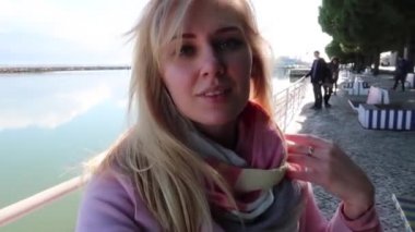 Güzel sarışın kadın görüntülü konuşma yapıyor. Açık havada akıllı telefon kullanıyor. Seyahat maceralarını paylaşıyor. Sosyal medya için selfie çeken bir kız. Portekiz tatili. Yavaş çekim