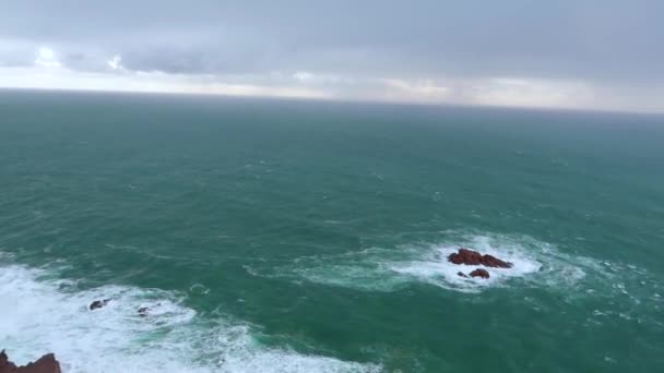 海の波が岩に砕けます 青い波 白い泡 岩と海の風景 崖から地平線の眺め どんよりした天気 — ストック動画