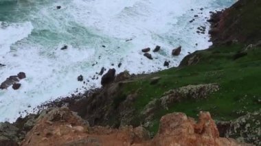 Okyanus dalgalar kayalar üzerine çökmesini. Mavi dalgalar, beyaz köpük ve kayalar ile deniz manzarası. Ufuk uçurumun üzerinden bir bakış. Bulutlu hava