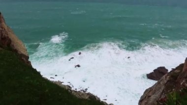 Okyanus dalgalar kayalar üzerine çökmesini. Mavi dalgalar, beyaz köpük ve kayalar ile deniz manzarası. Ufuk uçurumun üzerinden bir bakış. Bulutlu hava
