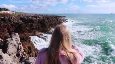 Güneşli havalarda buzlu çökmesini güçlü okyanus dalgaları. Saf güç, sergi doğanın zorlar. Güçlü enerji. Okyanus güç Dünya'ya karşı. Bir uçurum Okyanusu yakın oturan ve dalgaları seyretmekten sarışın genç kadın