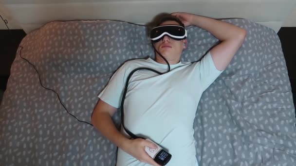 Jovem Homem Atraente Usa Dispositivo Massageador Ocular Deitado Cama Segurando — Vídeo de Stock