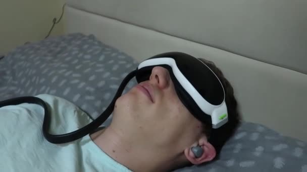 člověk používá masážní zařízení pro oči a hlava, zmírnit únavu, relaxace, odpočinek po práci na přenosném počítači