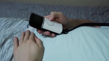 yatakta, bir uzaktan kumanda, yakın çekim tutan yatıyordu bir göz masaj cihazı, genç çekici adam kullanır