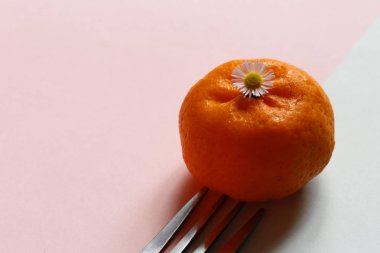 Pastel pembe ve mavi arka plan üzerinde paslanmaz çelik çatal ile turuncu kapatın. minimal fikir gıda ve meyve kavramı. 