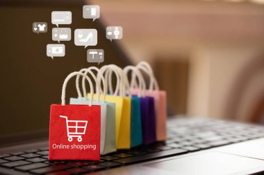 Çevrimiçi pazarlama ve E-ticaret kavramı: Not defteri klavyesinde ikon alışverişi yapan kağıt alışveriş torbaları. İnternet üzerinden ürün ve hizmetlerin satın alınması uygun ve güvenli malları satın alabilir