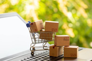 Çevrimiçi alışveriş, e-ticaret ve müşteri deneyimi kavramı: Laptop klavyesindeki alışveriş arabasındaki kutular
