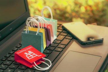 Klavyesinde cep telefonu olan kağıt alışveriş torbaları. Müşterilerin eşyalar, hizmetler veya malları uzaktan satın alabilecekleri internet üzerinden alışveriş fikirleri.