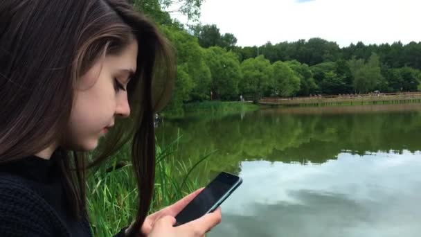 Hermosa Chica Parque Junto Lago Está Escribiendo Mensaje Teléfono Inteligente — Vídeos de Stock