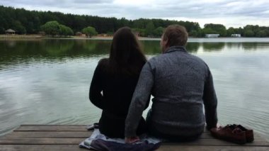 Göl kenarındaki platformda oturan mutlu çift