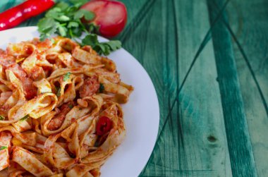 Beyaz bir tabak yeşil ahşap arka planda domates ezmeli baharatlı spagetti kopyalama alanı