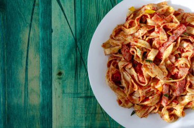 Beyaz bir tabak yeşil ahşap arka planda domates ezmeli baharatlı spagetti kopyalama alanı