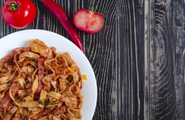 Beyaz tabak üzerinde domates ezmeli baharatlı spagetti.