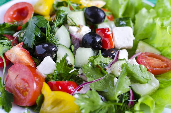 Sebze salatası salatalık biber peynirli zeytin beyaz tabakta yakın plan