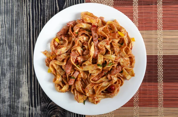 Beyaz tabak çok renkli arka planda domates ezmeli spagetti.