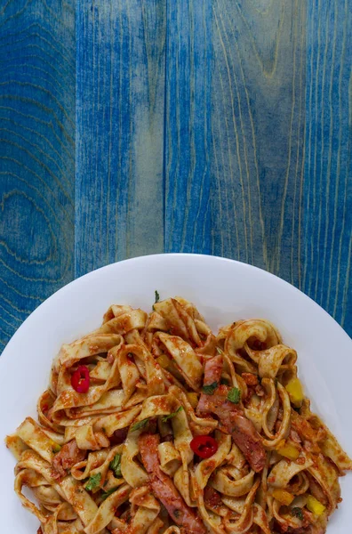 Dikey beyaz tabakta domates ezmeli baharatlı spagetti.