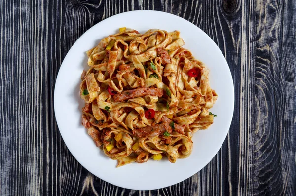 Beyaz tabak üzerinde domates ezmeli baharatlı spagetti.