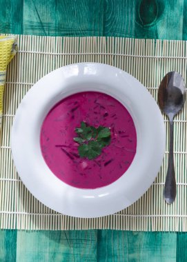 Pancar sebze çorbası, yeşil bir tabakta yeşil ahşap arka plan, dikey.