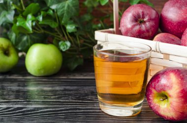 Doğal bir arka planda şeffaf bir bardakta kırmızı ve yeşil elma suyu.