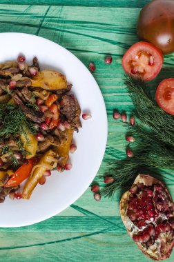 Domatesli fırında dana eti otlar ve nar meyveleriyle süslenmiş.