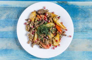 Domatesli fırınlanmış dana eti yeşillik ve nar arkaplanıyla süslenmiş.