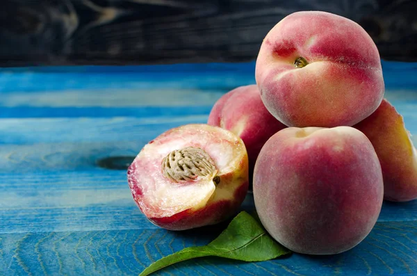 Sweet peaches and green leaf on wooden background