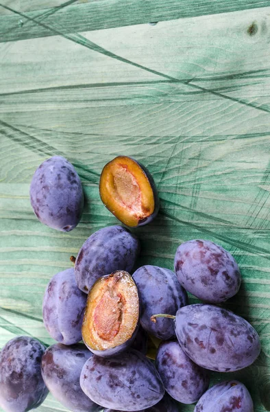 plum and dried plum on green wooden background top view prunes