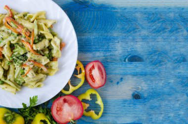 Beyaz tabakta peynirli ve sebzeli makarna. Fotokopi alanı üst görünümü parlak mavi arkaplan.