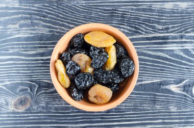 Koyu arkaplan manzaralı bir kasede kurutulmuş erik kayısı.