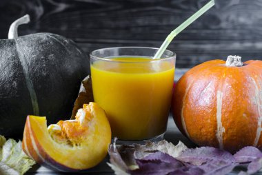 yeşil ve portakal kabağı ve kabak suyu şeffaf kase içinde ahşap arka planda