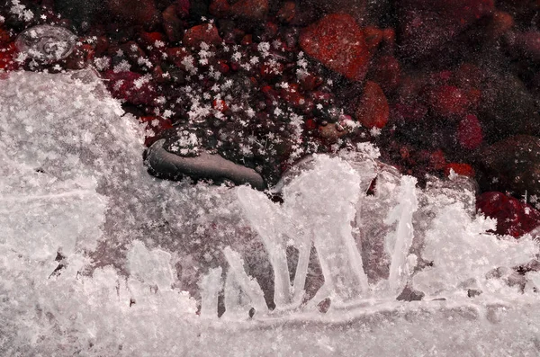 background of small stones covered with transparent ice large snow crystals on river ice