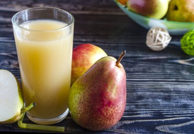 a glass of pear juice and pears on a dark wooden background close up