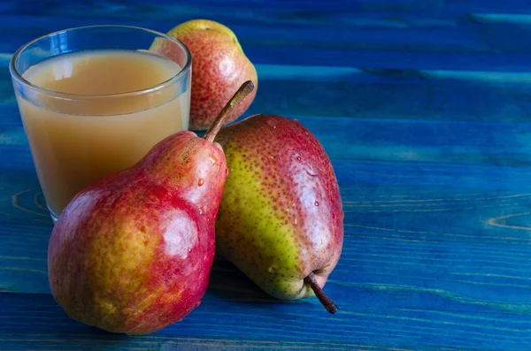 transparent glass of pear juice and juicy pears on a rich blue background place under the text