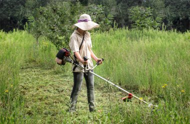 Çim kesme. İş elbiseleri kız bahçede çim mows. Büyük şapka ve gözlük kızı korumak. Kızlar kalıplaşmış değiştirme. Güçlü kadın kavramı