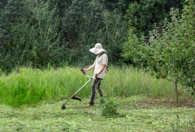 Çim kesme. İş elbiseleri kız bahçede çim mows. Büyük şapka ve gözlük kızı korumak. Kızlar kalıplaşmış değiştirme. Güçlü kadın kavramı